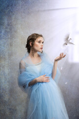 pregnant woman with a doves against the background of the open window for Mother Earth Day. Photo...