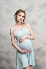 Beautiful pregnant woman with flowers on belly. Young woman in maternity waiting for baby birth. Pregnancy, Motherhood, Mother's Day Holiday concept.
