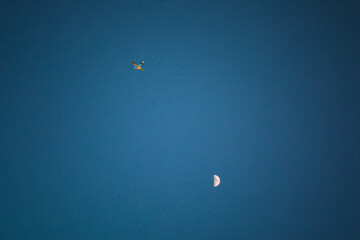 A plane is flying in the blue skies over the moon