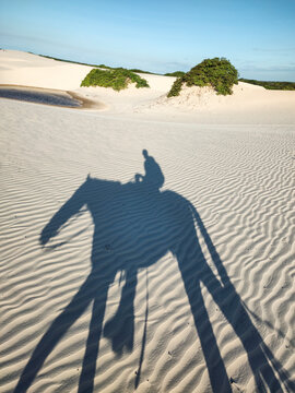 Beautiful view to shadow of man riding horse on sand dunes