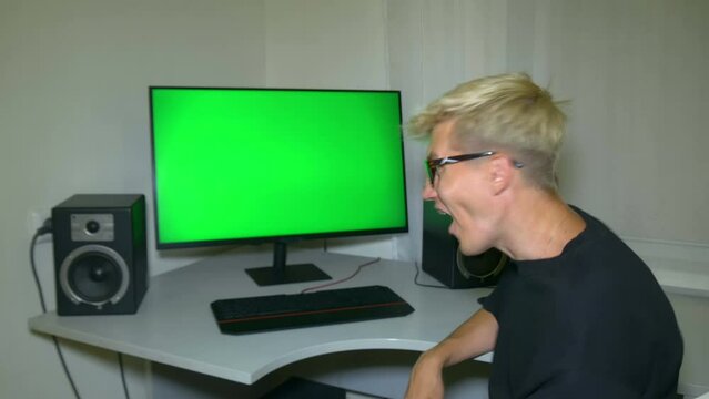 Guy is very happy with what is shown on the computer screen. Chromakey on computer screen. Video with a chroma key on the screen to insert any video or image.