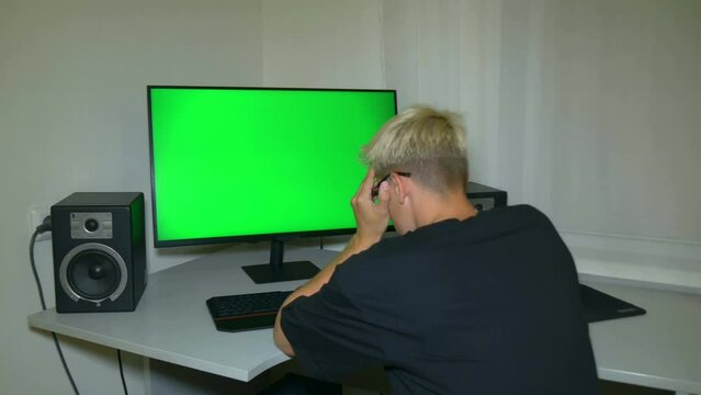 Guy is very disappointed with what is shown on the computer screen. Chromakey on computer screen. Video with a chroma key on the screen to insert any video or image.