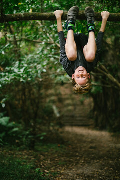 Pre teen child boy climbs tree in forest on nature adventure