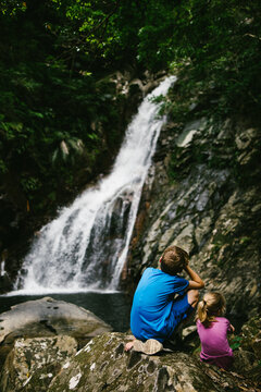 A brother and sister at a waterfall after a hike in tropical forest