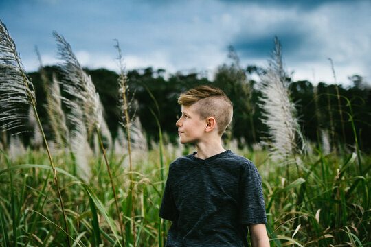 Pre teen boy in front of grass field and forest