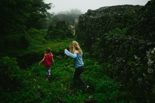 Children hike through green tropical forest with wall remains