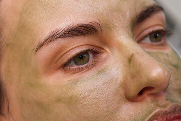 Woman patient portrait, prepared for LED phototherapy for the face. Girl with green gel with seaweed photosensitizer. Facial care. Light therapy in clinic, anti-age procedure. Face closeup