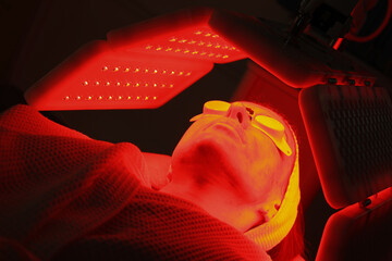 Express facial treatment with led therapy. Beautiful girl on a light therapy procedure. LED lamp...