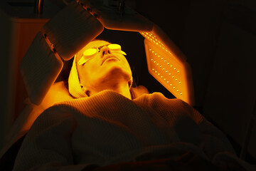 Express facial treatment with led therapy. Beautiful girl on a light therapy procedure. LED lamp...