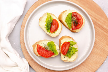 Bruschetta sandwich bread toast with soft white cheese ricotta,fresh tomatoes,basil greenery on a wooden cutting board.Tasty healthy vegetarian food,Italian cuisine appetizer. top view flat lay