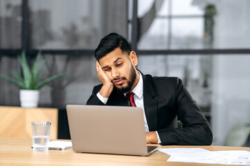 Fatigue, chronic sleep deprivation. Sleepy arabian or indian business man in a suit, sit at...