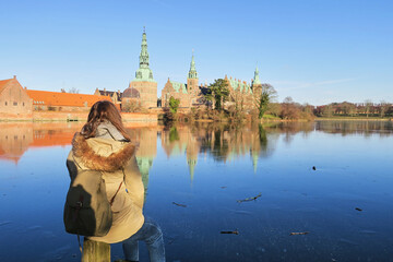 Young girl looking at lake and Rosenborg castle in Copenhagen