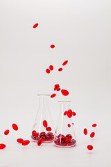Krill oil red capsules in laboratory transparent flasks on a white background.natural omega three acids.Source of omega 3 fatty acids. Flying red capsules krill oil.Natural supplements 
