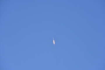 Distant Rocket Launch clear Blue Day with exhaust trail and sunny sky