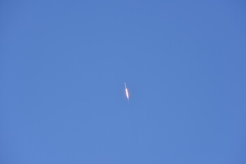 Distant Rocket Launch clear Blue Day with exhaust trail and sunny sky