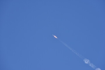 Distant Rocket Launch clear Blue Day with exhaust trail and sunny sky