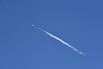 Distant Rocket Launch clear Blue Day with exhaust trail and sunny sky