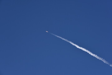 Distant Rocket Launch clear Blue Day with exhaust trail and sunny sky
