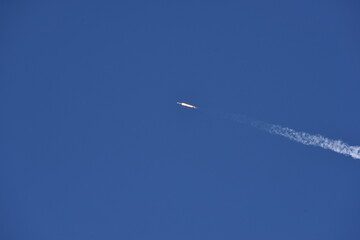 Distant Rocket Launch clear Blue Day with exhaust trail and sunny sky