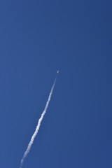 Distant Rocket Launch clear Blue Day with exhaust trail and sunny sky