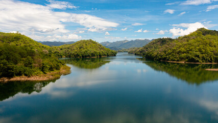 A river among mountains and hills with a reflecting blue sky and clouds. Randenigala reservoir, Sri Lanka.