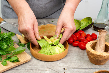 peeled avocado and extracted pit in the hands of the cook. The avocado is ready to serve.
