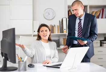 Upset man standing next to disgruntled female boss in office