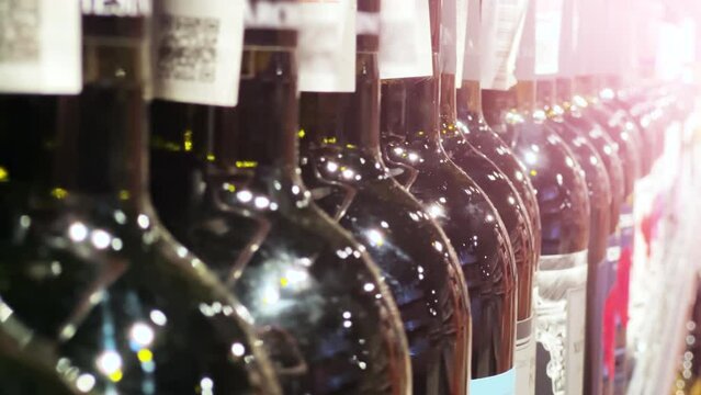 Red wine bottles line up on the shelf of a liquor store (ABC store) or supermarket. Close up shot