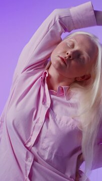 Young albino woman posing against a plain background, vertical video