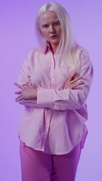 Young albino woman posing against a plain background, vertical video