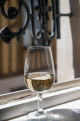 Tasting of white grand cru classe chablis wine with old French houses on background, Burgundy, France