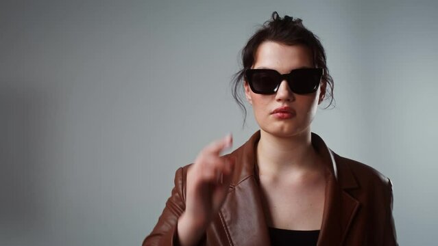 Woman putting on sunglasses posing in studio