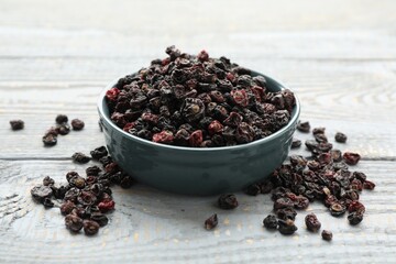Dried black currants and bowl on grey wooden table