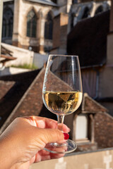 Tasting of white grand cru classe chablis wine with old French houses on background, Burgundy, France