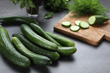 Whole and cut fresh ripe cucumbers on grey table