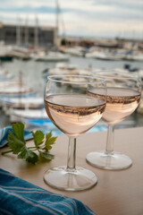 Rose wine in glasses served on outdoor terrace with view on old fisherman's harbour with colourful boats in Cassis, Provence, France