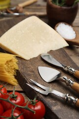 Cheese knives and fork on wooden board, closeup. Cooking utensils