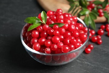 Fresh cranberry in bowl on dark grey table, closeup