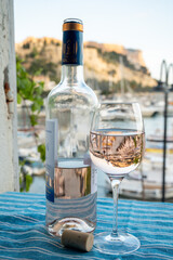 Rose wine in glass and bottle served on outdoor terrace with view on old fisherman's harbour with...