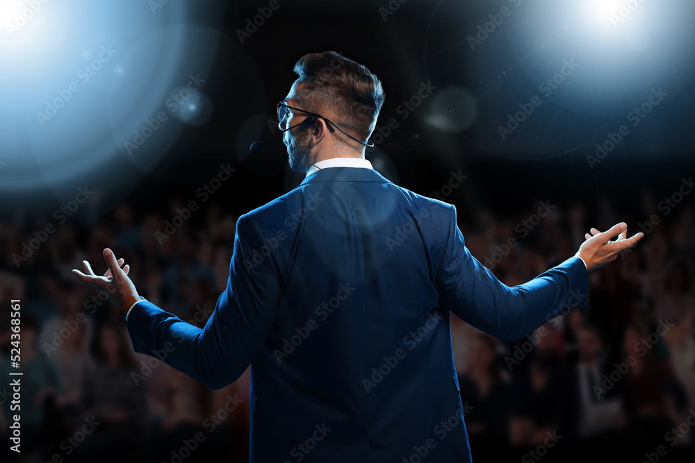 Wall mural motivational speaker with headset performing on stage, back view