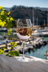 Rose wine in glass served on outdoor terrace with view on old fisherman's harbour with colourful boats in Cassis, Provence, France