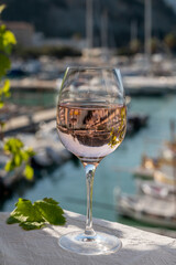 Rose wine in glass served on outdoor terrace with view on old fisherman's harbour with colourful boats in Cassis, Provence, France