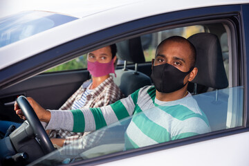 Young adult man and woman wearing protective face masks for prevent viral spread travelling together by car