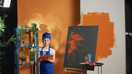 Portrait of small child painting artwork design on canvas, using artistic aquarelle palette and paintbrush. Young girl learnign to paint masterpiece with watercolor and brush, creative skills.