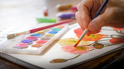水彩絵の具で花のイラストを描いている人物