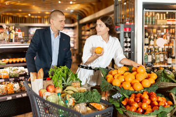 Young couple searching fresh vegetables and fruits while shopping in greengrocery