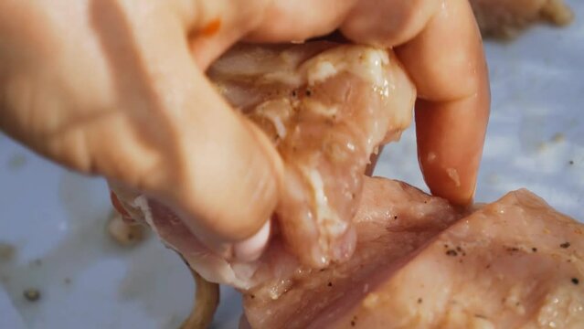 A girl cuts pieces of mca with a knife on a cutting board for cooking shish kebab. Very cool close-up of hands