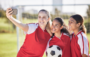 Selfie, soccer and sports team smiling and feeling happy while posing for a social media picture. Diverse and young girls standing together on a football field. Friends and teammates enjoying a match - Powered by Adobe