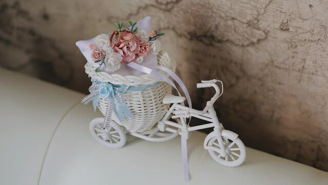 A small toy bicycle with flowers and gold rings. Close-up shooting of festive items