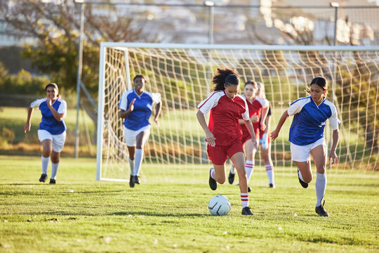 Sports team, girl soccer and kick ball on field in a tournament. Football, competition and athletic female teen group play game on grass. Fit adolescents compete to win match at school championship.